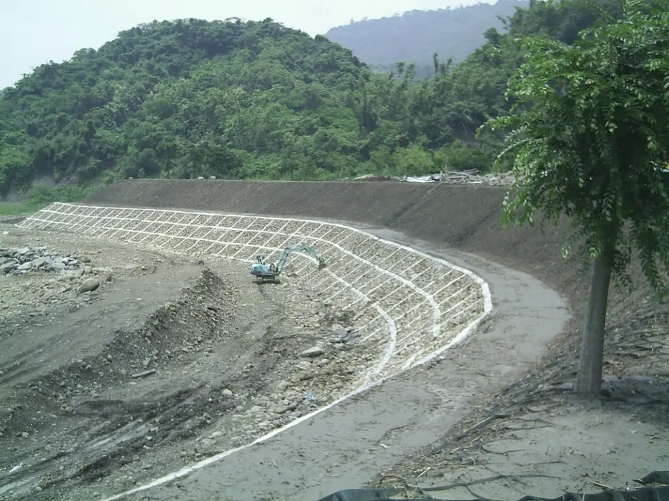 弧形邊坡坡面上的白色格狀分格,中間有一台小型挖土機作業